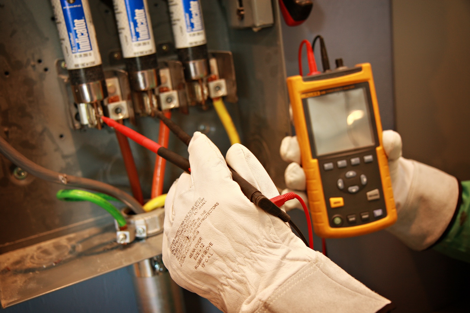 Electrical specialist using test leads and a handheld instrument inside energized distribution equipment